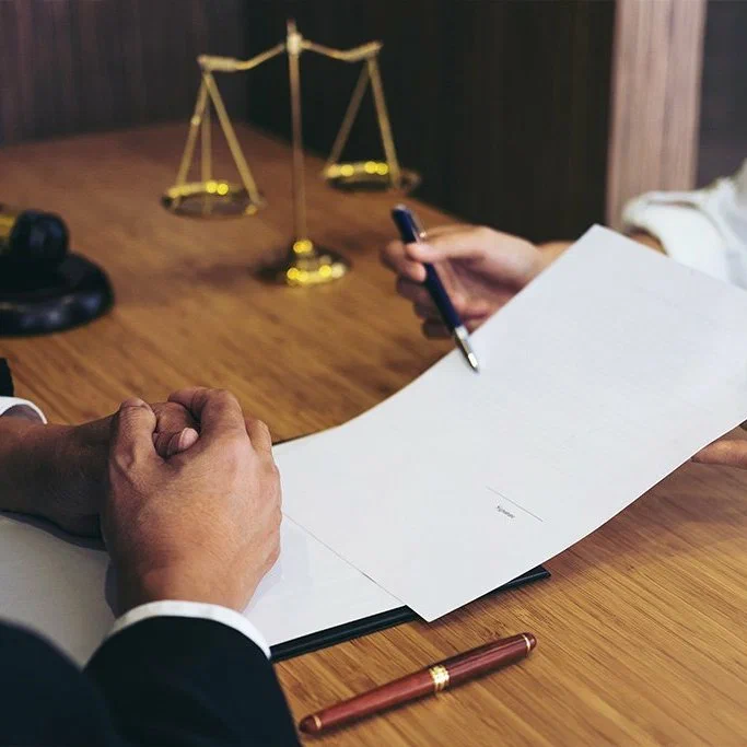 Two people reviewing and signing a legal document at a desk.